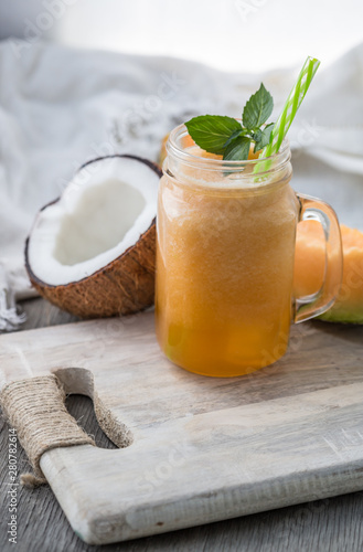 Photo of melon smoothie in jar with straw on light background. Fresh organic Smoothie. Health or detox diet food concept. photo