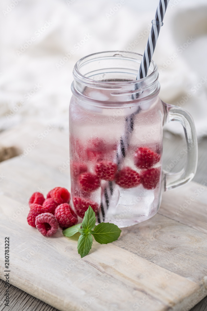 Home fizzy drink with ice and raspberry on a light background, selective focus. Photo of home made refreshing beverage Home fizzy drink with ice and raspberry on a light background, selective focus. Photo of home made refreshing beverage