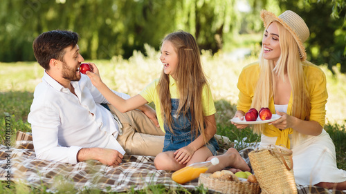 Happy family relaxing in park, eating fruits