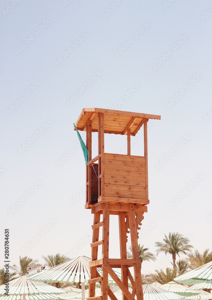 Wooden baywatch tower on the beach against the beautiful sky and beach umbrellas