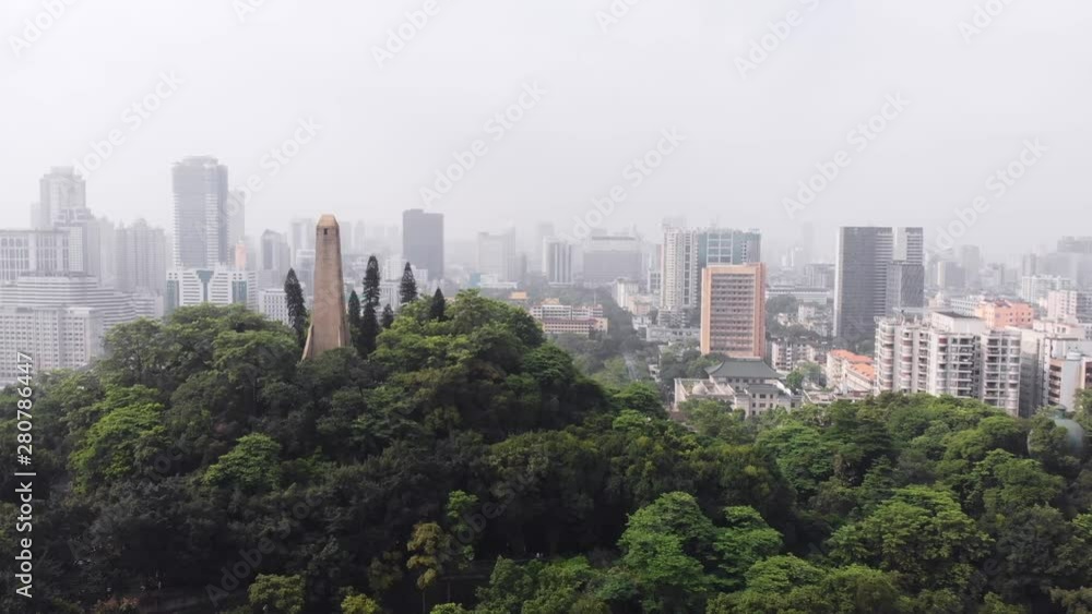 Flying low over dense trees, among which there is a tower. Gradually overlooking the city of Guangzhou. China Flying low over dense trees, among which there is a tower. Gradually overlooking the city of Guangzhou. China