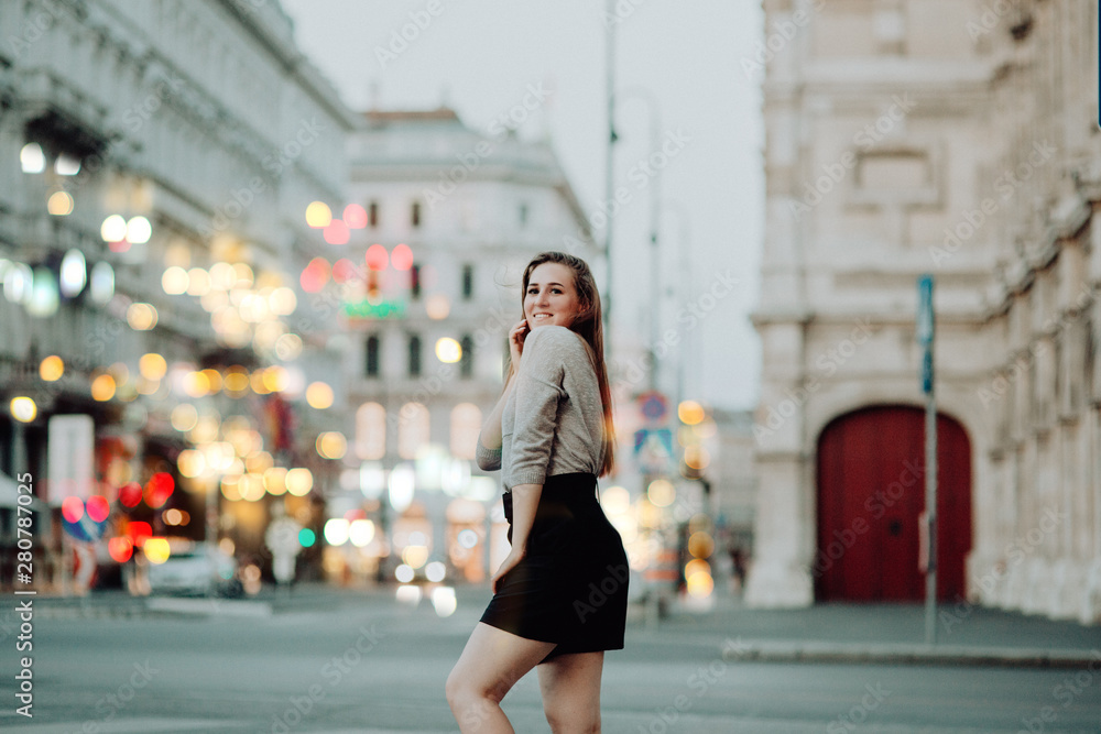Face portrait of attractive young woman smiling at the camera on the city street background