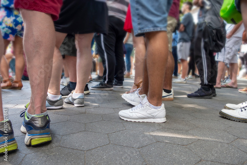 Crowd of standing people watching and event  shorts  feet and legs on a casual weekend summer day