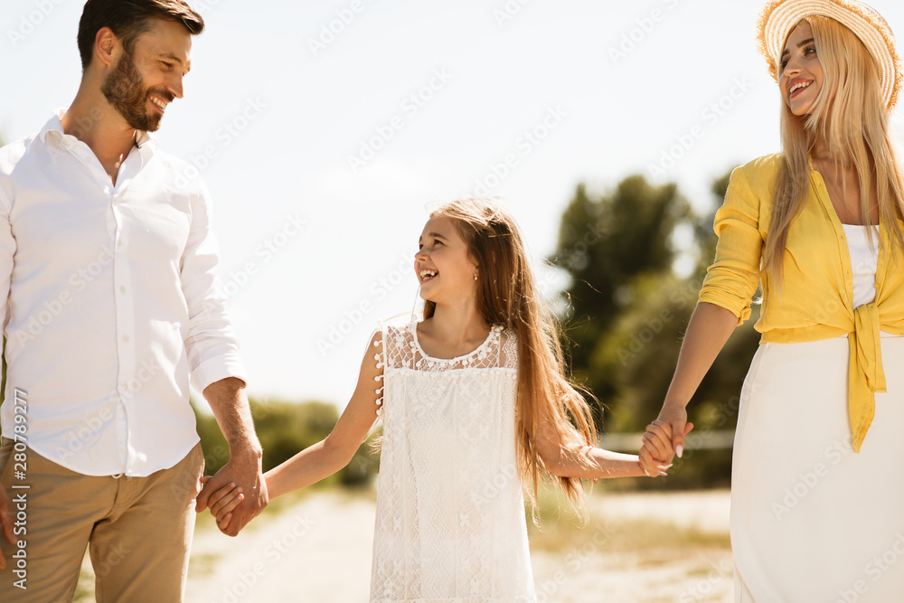 Parents and child walking, holding hands outdoors Parents and child walking, holding hands outdoors