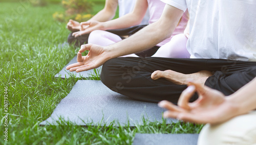Group of people sitting in lotus position outdoors
