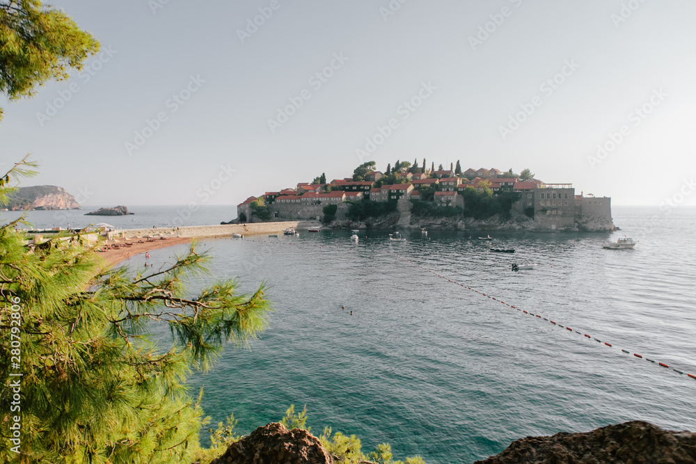 People are sunbathe and swim on the beach of the resort Sveti Stefan in Montenegro