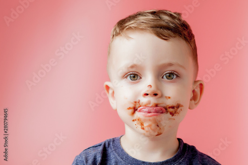 Little boy eating chocolate. Cute happy boy smeared with chocolate around his mouth. Child concept. photo