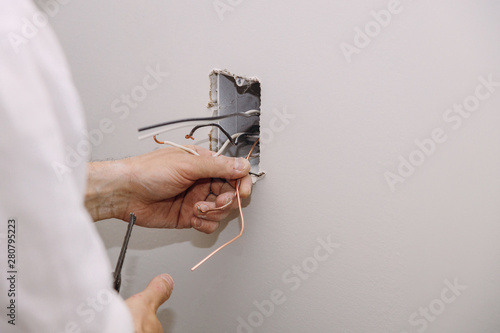 Unfinished electrical mains outlet socket with electrical wires and connector installed in plasterboard drywall