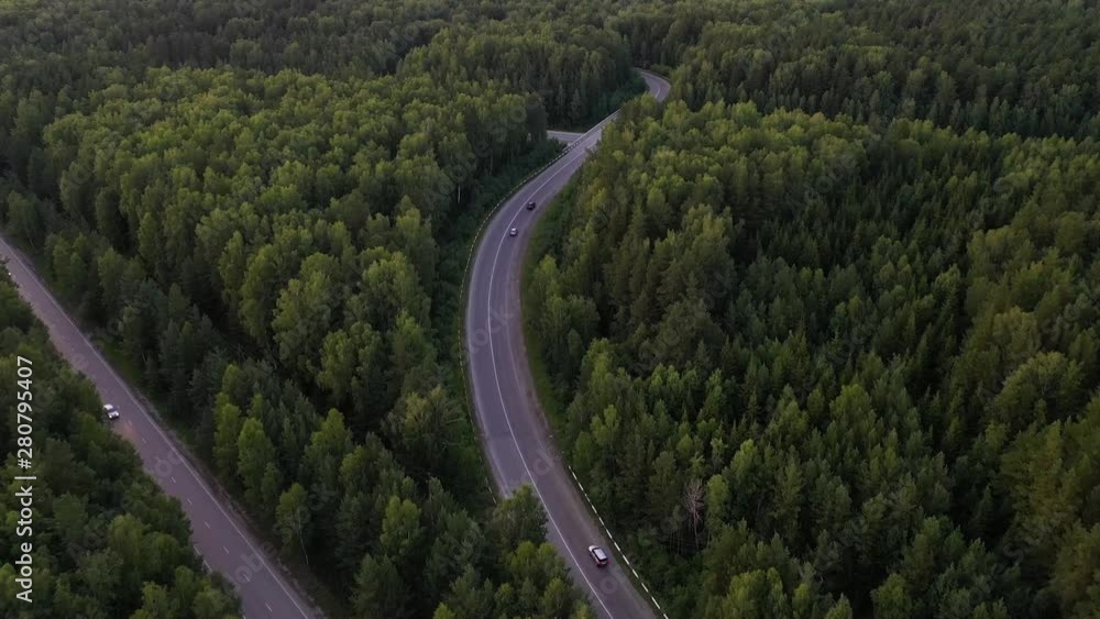Aerial view flying over road with car moving, that through lane green forest. Car driving along the forest road. AERIAL: Car driving through pine forest. Drone shot from above Aerial view flying over road with car moving, that through lane green forest. Car driving along the forest road. AERIAL: Car driving through pine forest. Drone shot from above