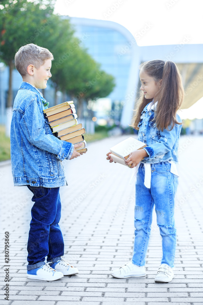 Naklejka premium Little students hold a lot of books. The concept is back to school, education, reading, friendship and family.