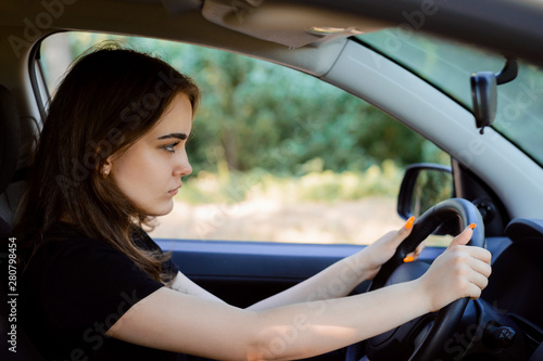 Concentrated young woman driver drives fast car and controlling the situation around. Concept of careful and concentrated driving
