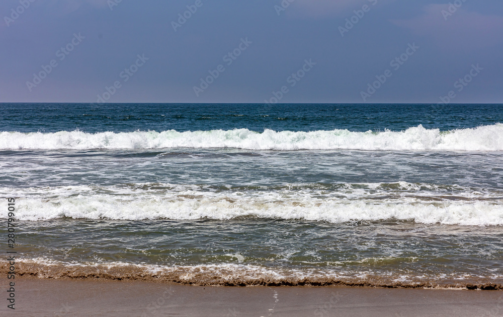 Sandy beach empty. Blue sky, blue sea with waves