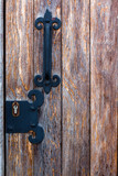Metallic door handle on a wooden door. The handle and the door is antique painted in black paint.