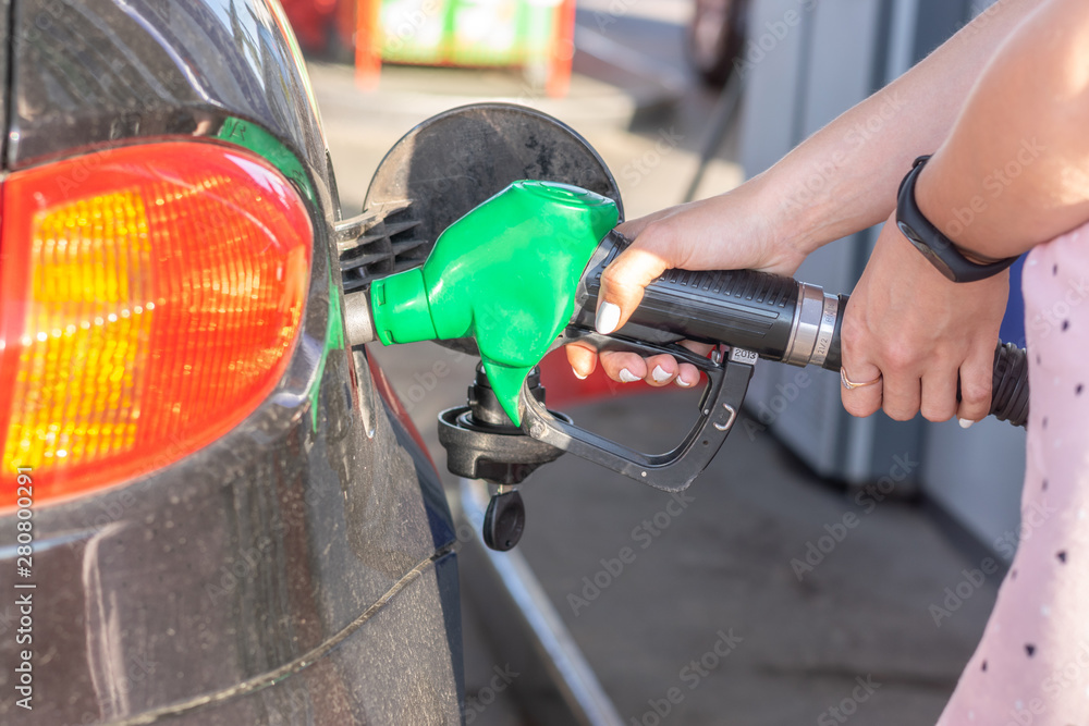 Gas pump nozzle in the fuel tank of bronze car, refuel petroleum to vehicle at gas station. 
