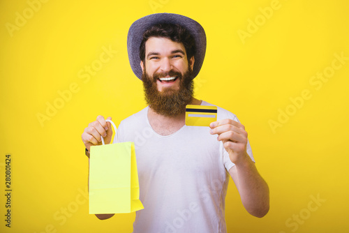 Portrait of smiling happy man holding yellow credit card and shopping bag