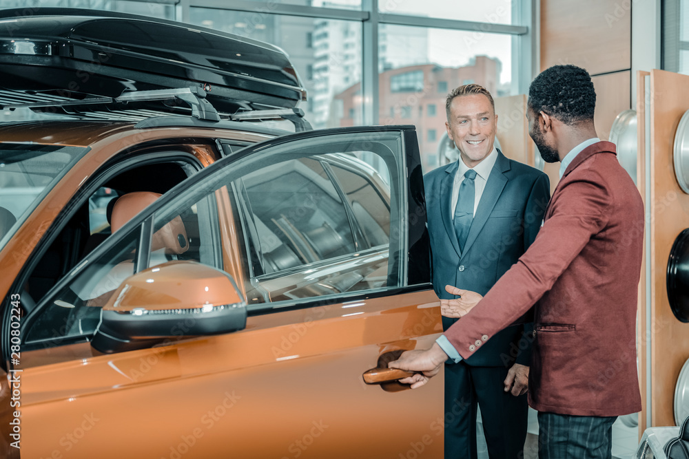 Consultant asking his client to sit in the car. Consultant asking his client to sit in the car.