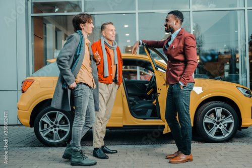 Two men talking to a car dealer after buying automobile. © Viacheslav Yakobchuk