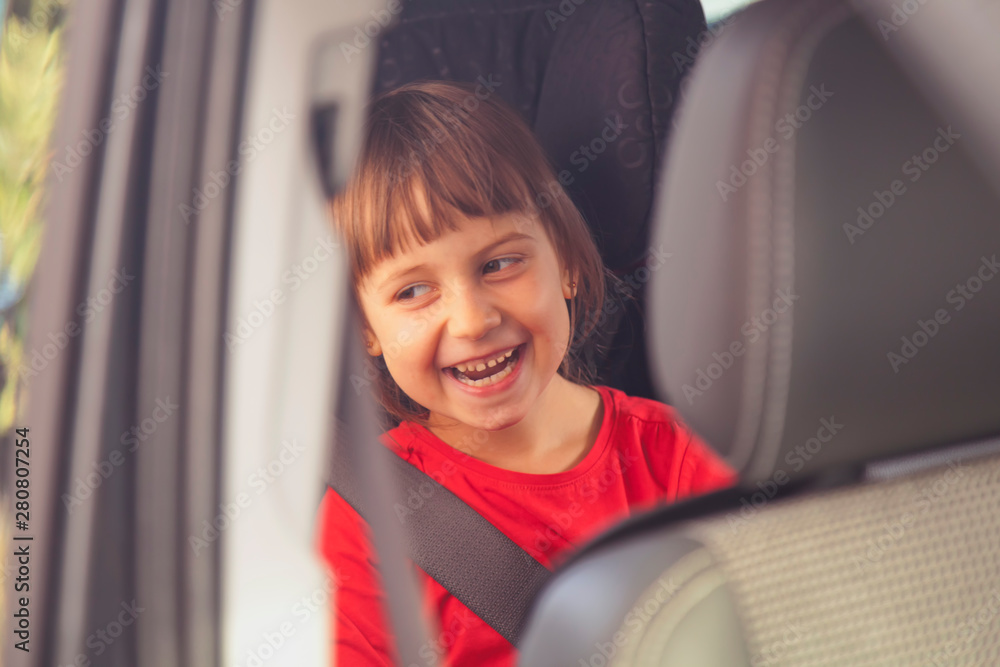 Transport, safety and road trip concept. Happy cute little child girl sitting in car seat.