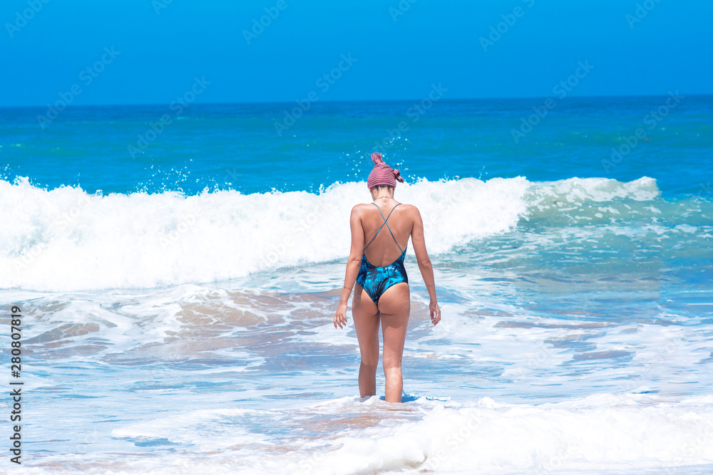 Lifestyle during holiday - young beautiful woman enjoying splashes of waves on the beach