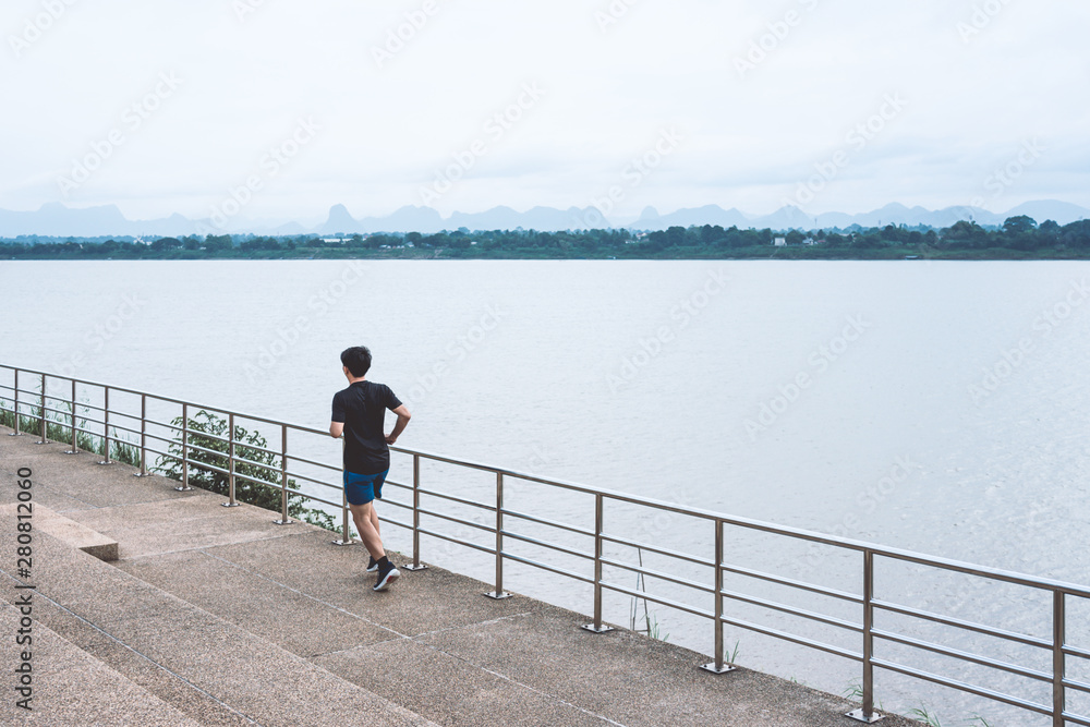 Young man running on the street with a view of the river in the morning.