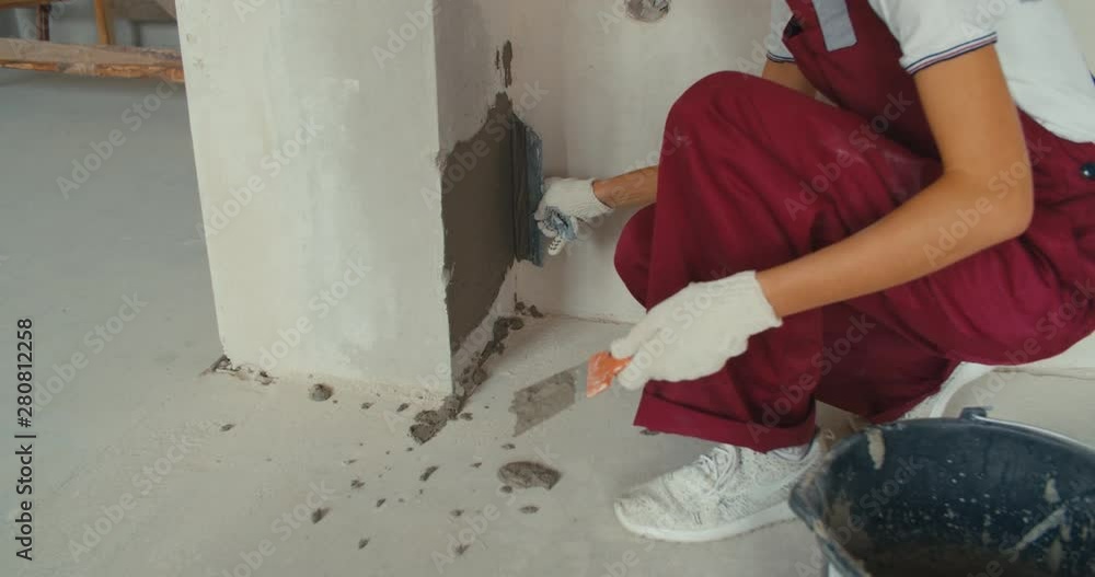Closeup of repairman hand plastering a wall with putty knife or spatula Closeup of repairman hand plastering a wall with putty knife or spatula