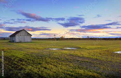 Barn in the middle of fields with sunset background