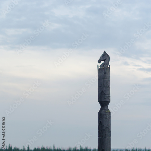 Yakut pole with horse Serge stands with the head of a horse made of wood on the background of endless tundra and forest under the clouds. photo