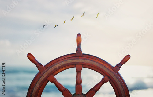 Obraz na plátně vintage nautical detail of a steering wheel of a ship in front of the sea at sun