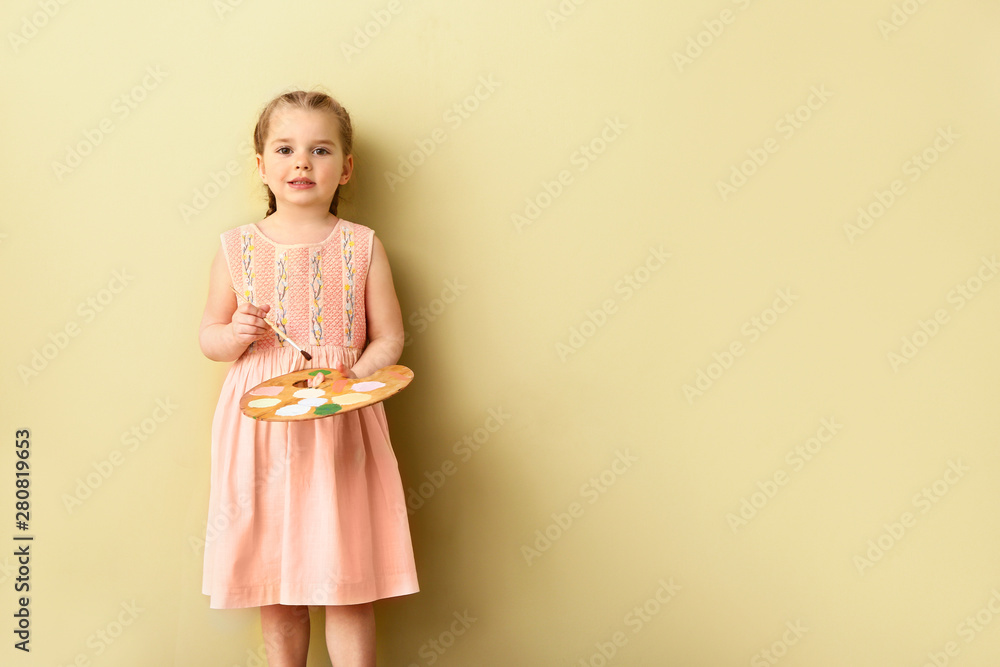Little girl with brush and palette near color wall Little girl with brush and palette near color wall