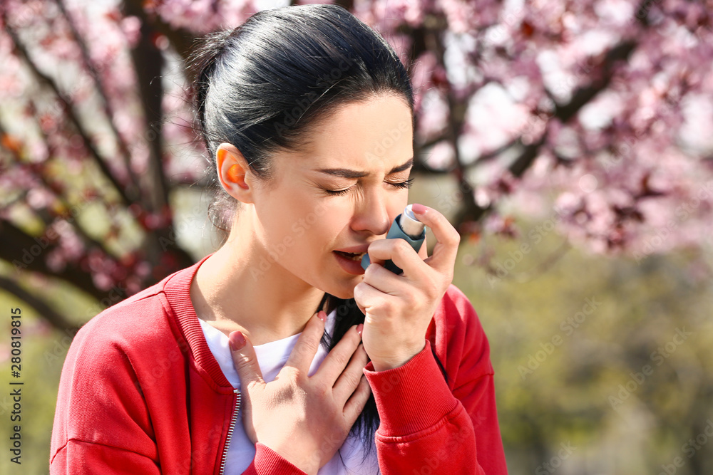 Woman with inhaler having asthma attack on spring day