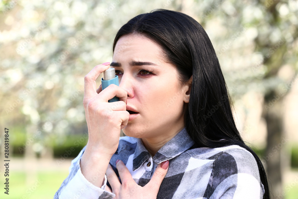Woman with inhaler having asthma attack on spring day Woman with inhaler having asthma attack on spring day