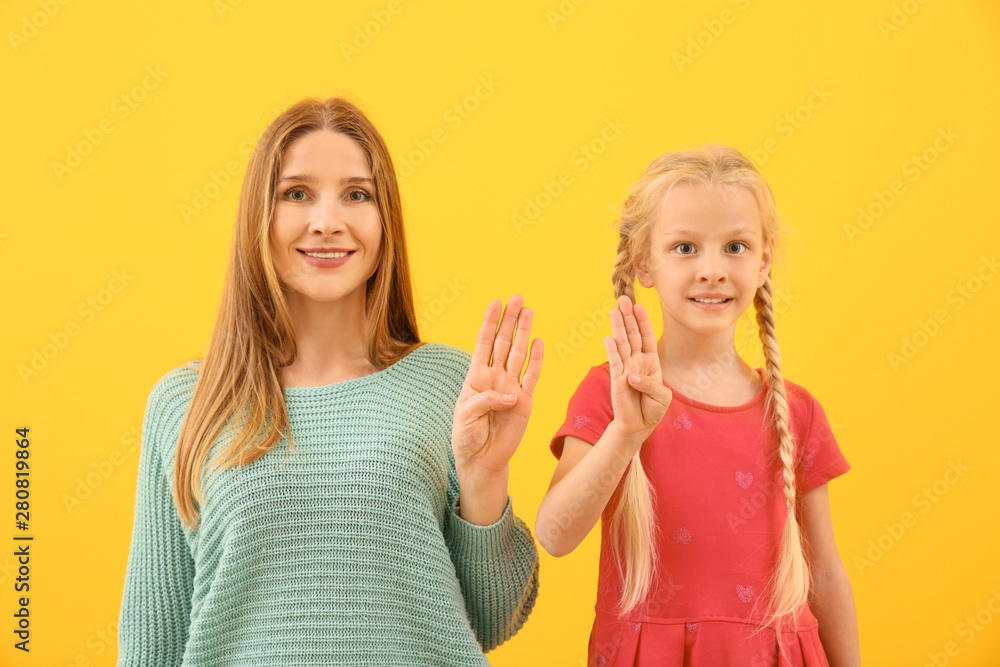 Little deaf mute girl and her mother using sign language on color background Little deaf mute girl and her mother using sign language on color background