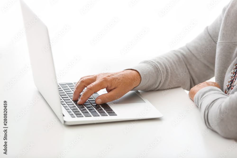 Elderly woman with modern laptop sitting at table, closeup Elderly woman with modern laptop sitting at table, closeup