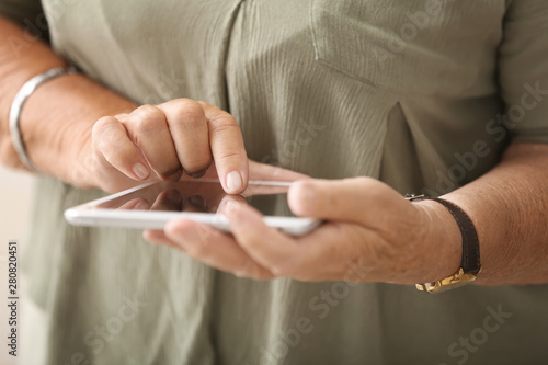 Elderly woman with modern tablet computer, closeup