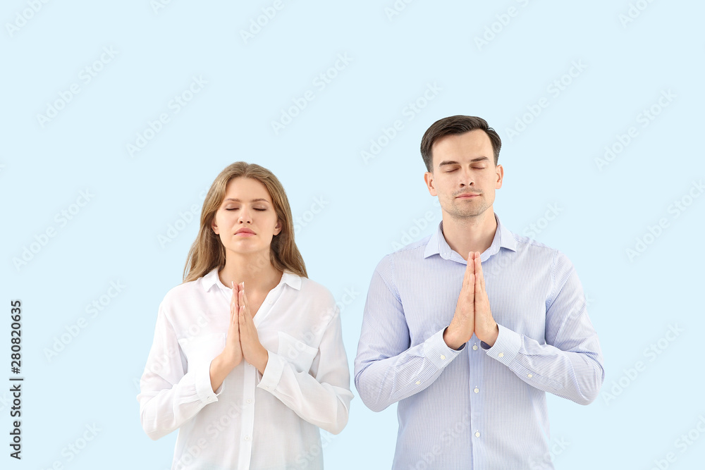 Religious couple praying to God on light color background Religious couple praying to God on light color background