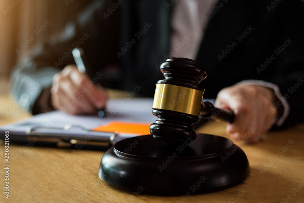 justice and law concept.Male judge in a courtroom the gavel, working with digital tablet computer on wood table in sun light. justice and law concept.Male judge in a courtroom the gavel, working with digital tablet computer on wood table in sun light.