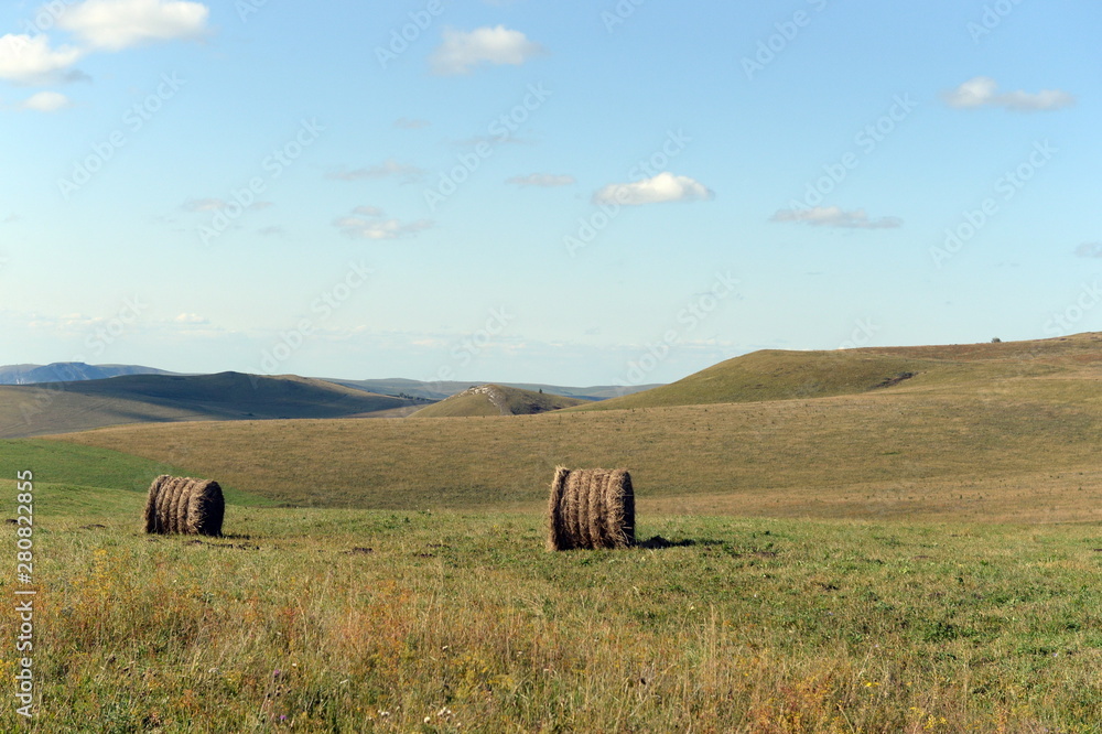 Rural landscape with harvested hay rolls in the foothills of the Altai mountains. Western Siberia. Russia Rural landscape with harvested hay rolls in the foothills of the Altai mountains. Western Siberia. Russia