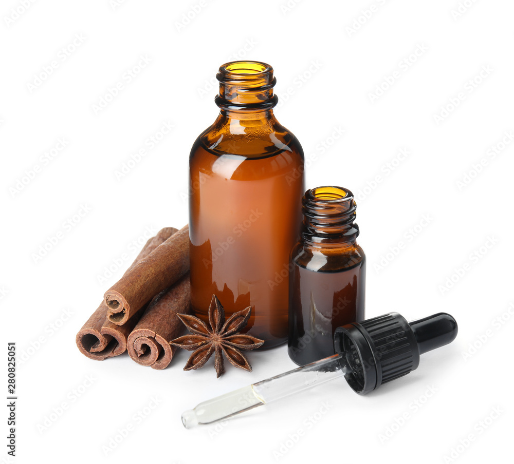 Bottles of essential oils and cinnamon sticks on white background Bottles of essential oils and cinnamon sticks on white background
