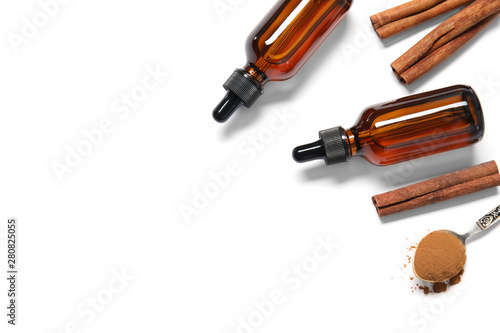 Flat lay composition with cinnamon essential oil on white background. Space for text