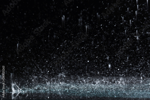 Fotografia Heavy rain falling down on ground against dark background