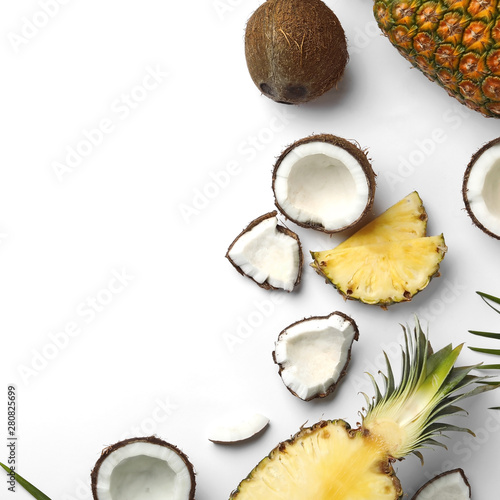 Composition with coconuts, juicy pineapples and leaves on white background, top view