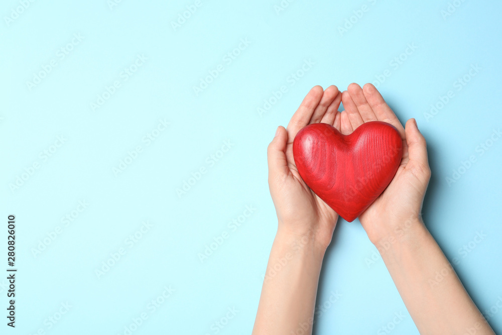 Fototapeta premium Woman holding heart on blue background, top view with space for text. Donation concept