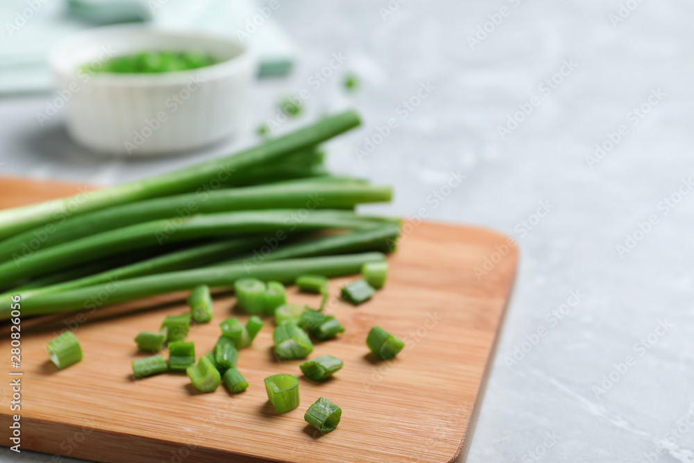 Wooden board with bunch of fresh green onion on table, closeup