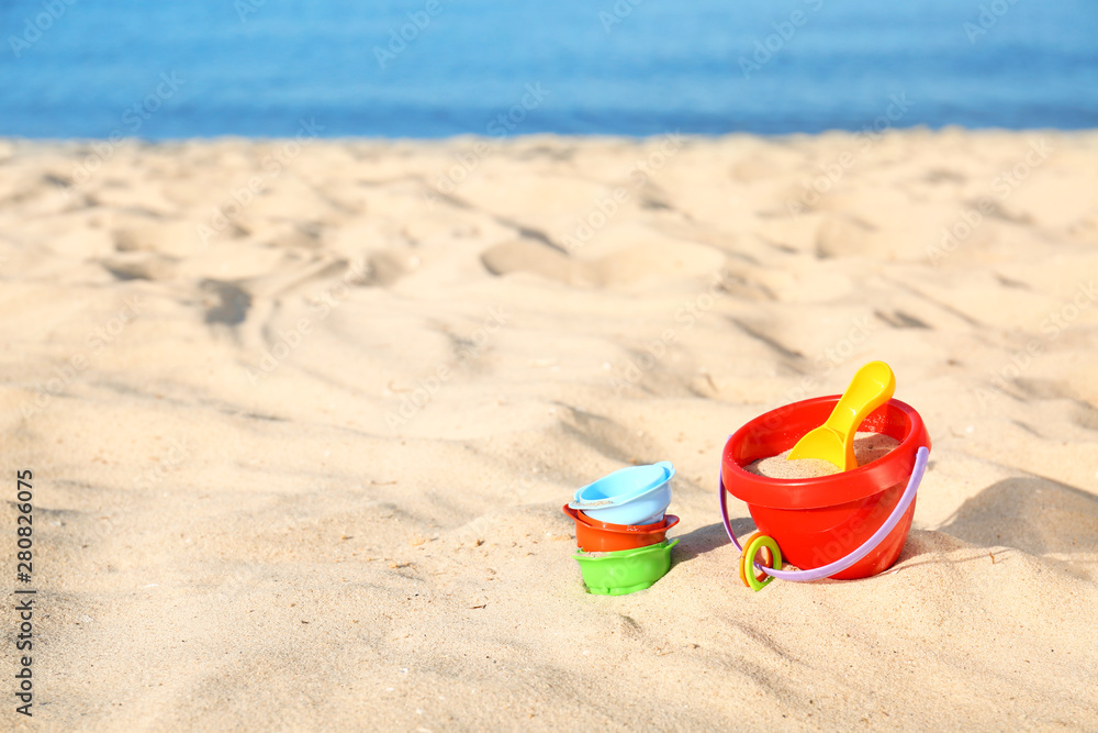 Set of plastic beach toys on sand near sea. Space for text Set of plastic beach toys on sand near sea. Space for text