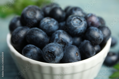 Bowl full of tasty ripe blueberries on table, closeup