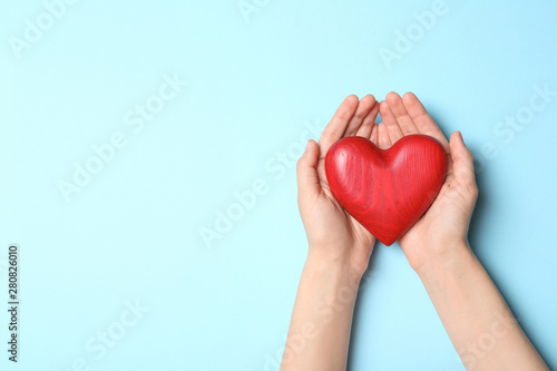 Fototapeta Naklejka Na Ścianę i Meble -  Woman holding heart on blue background, top view with space for text. Donation concept