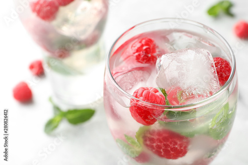 Glass of refreshing drink with raspberry and mint on table, closeup view. Space for text