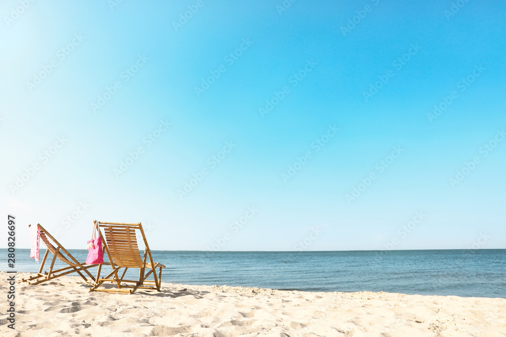 Empty wooden sunbeds and beach accessories on sandy shore Empty wooden sunbeds and beach accessories on sandy shore