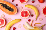 Flat lay composition with condoms and exotic fruits on pink background. Erotic concept