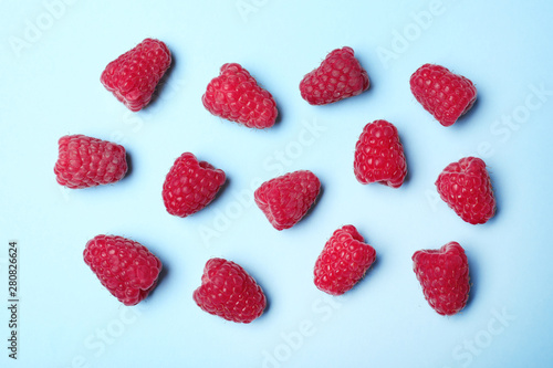 Flat lay composition with delicious ripe raspberries on blue background
